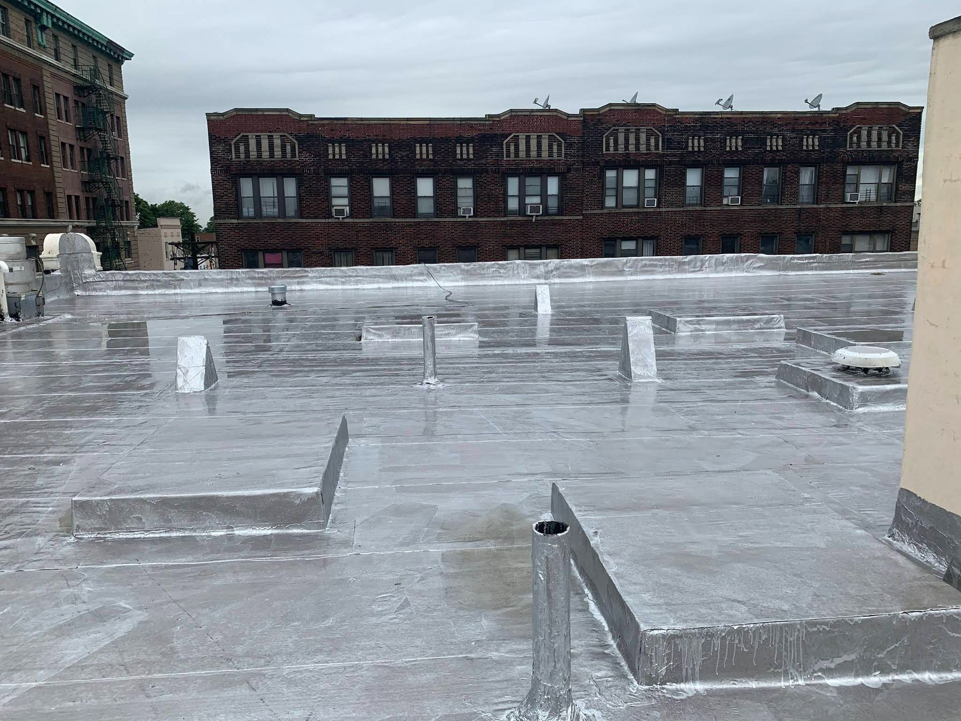 A roof with a lot of water on it and a building in the background.