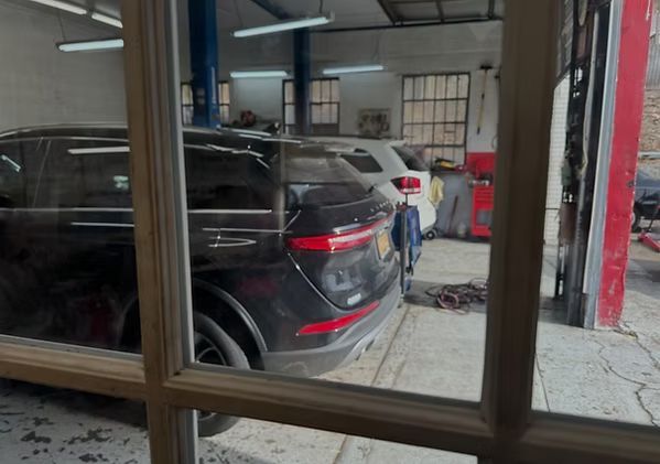Black SUV parked inside a garage, viewed through window panes | New Pegasus Automotive
