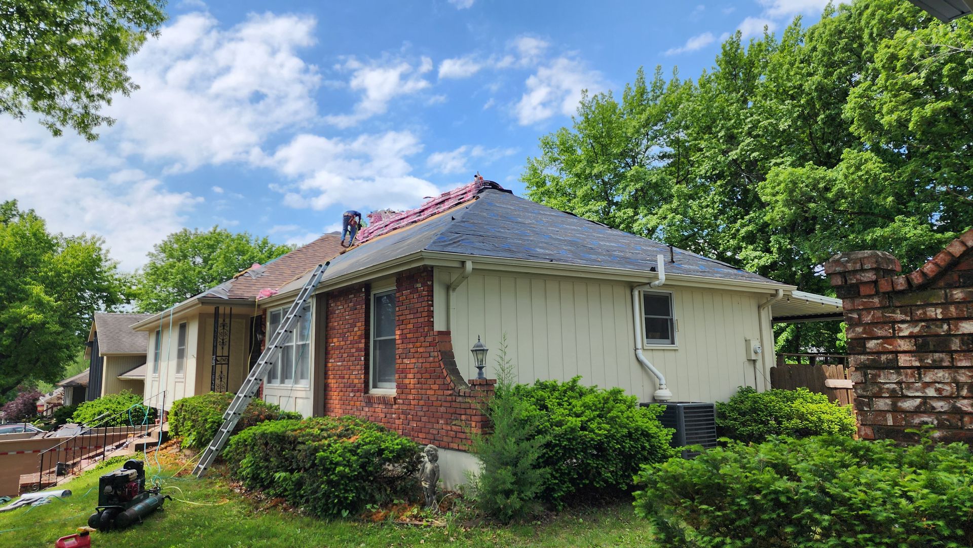 House with roof in the process of being replaced; ladder and roofing materials visible.