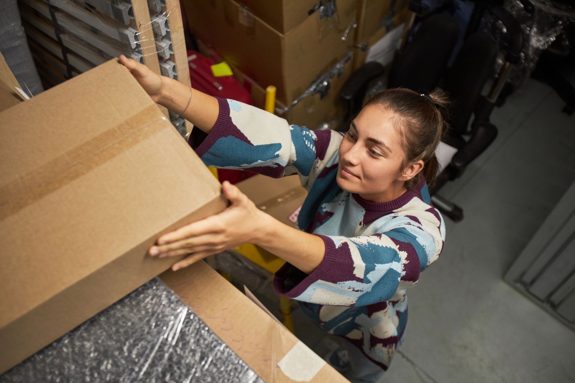 Person packing a cardboard box with bubble wrap in a storage room
