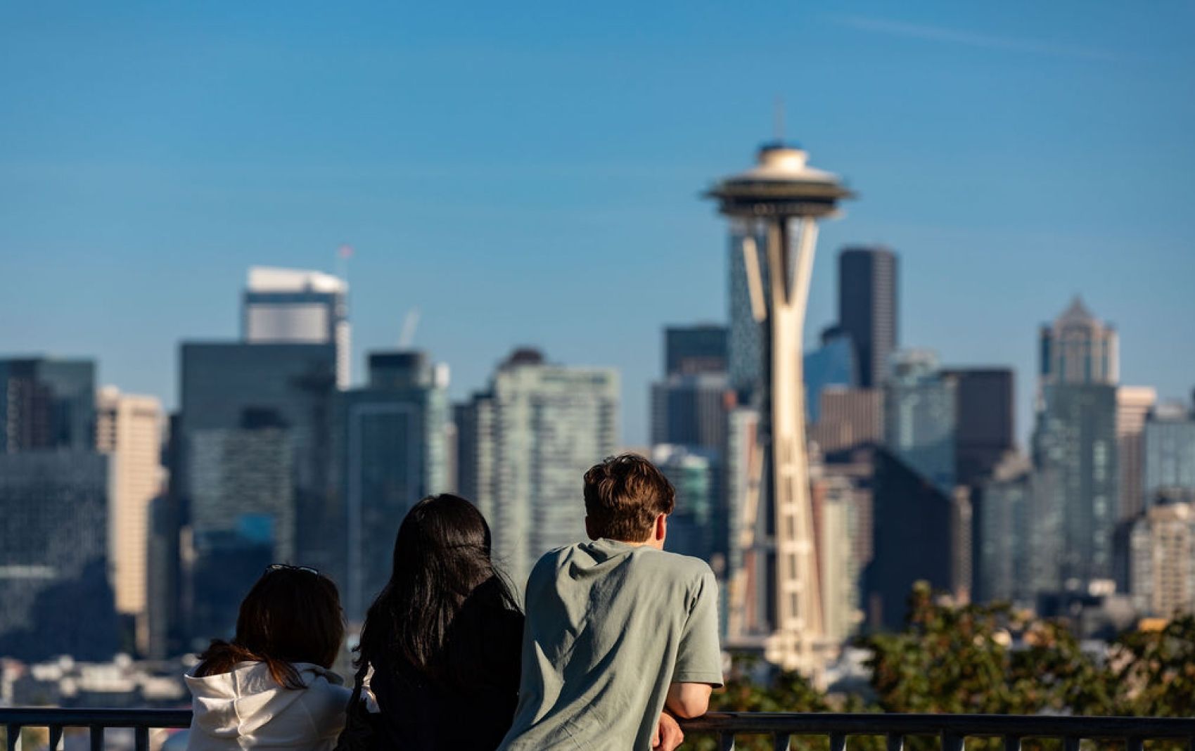 A man and two women are looking at the skyline of seattle