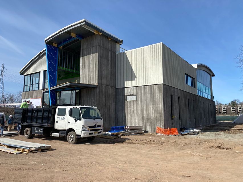 Construction site with a white truck beside a partially clad modern building under a blue sky