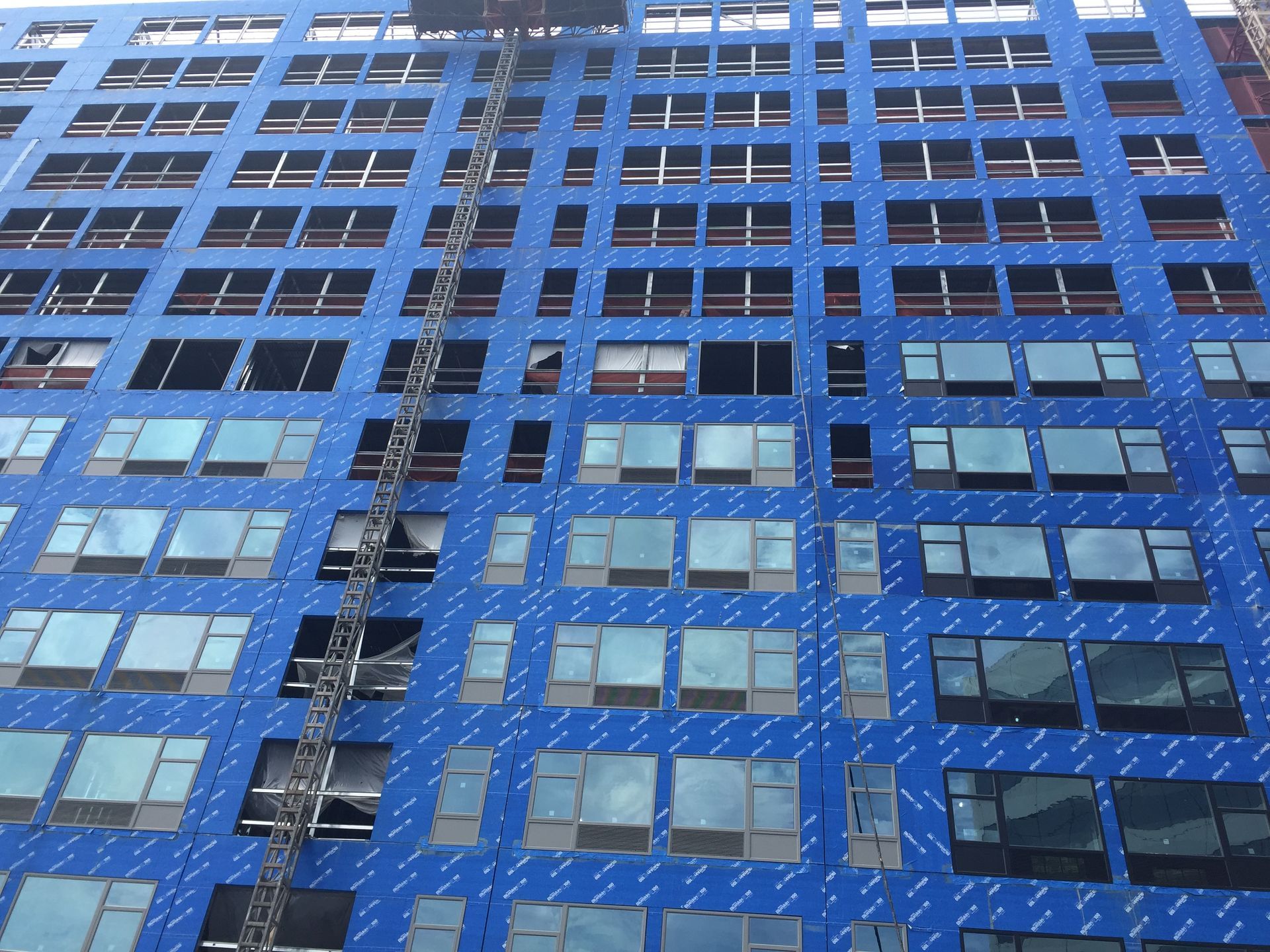 Blue high-rise building with many windows and a metal fire escape facade