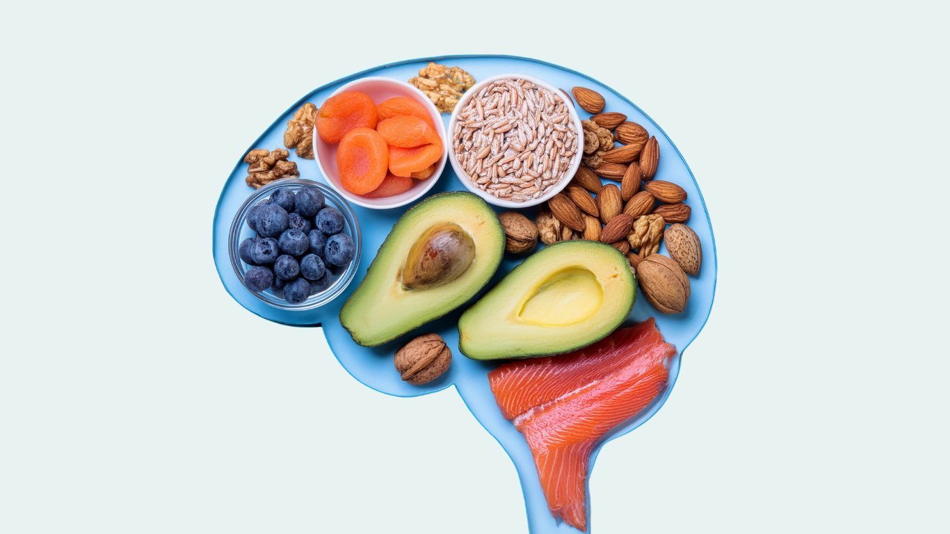 An outline of a brain with different foods fit inside of it including avocado, salmon, nuts, blueberries and carrots