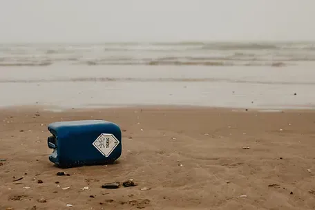 A blue plastic container is sitting on a sandy beach near the ocean.
