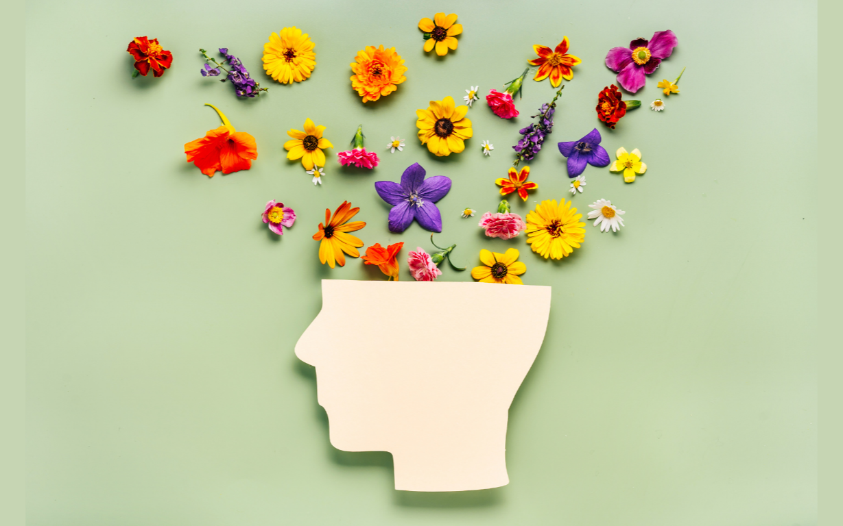 A side profile of a head with colorful flowers pouring out from the top