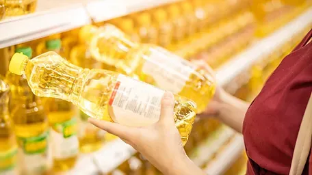 A woman is holding a bottle of oil in a supermarket.