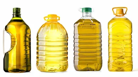 Four bottles of oil are lined up in a row on a white background.