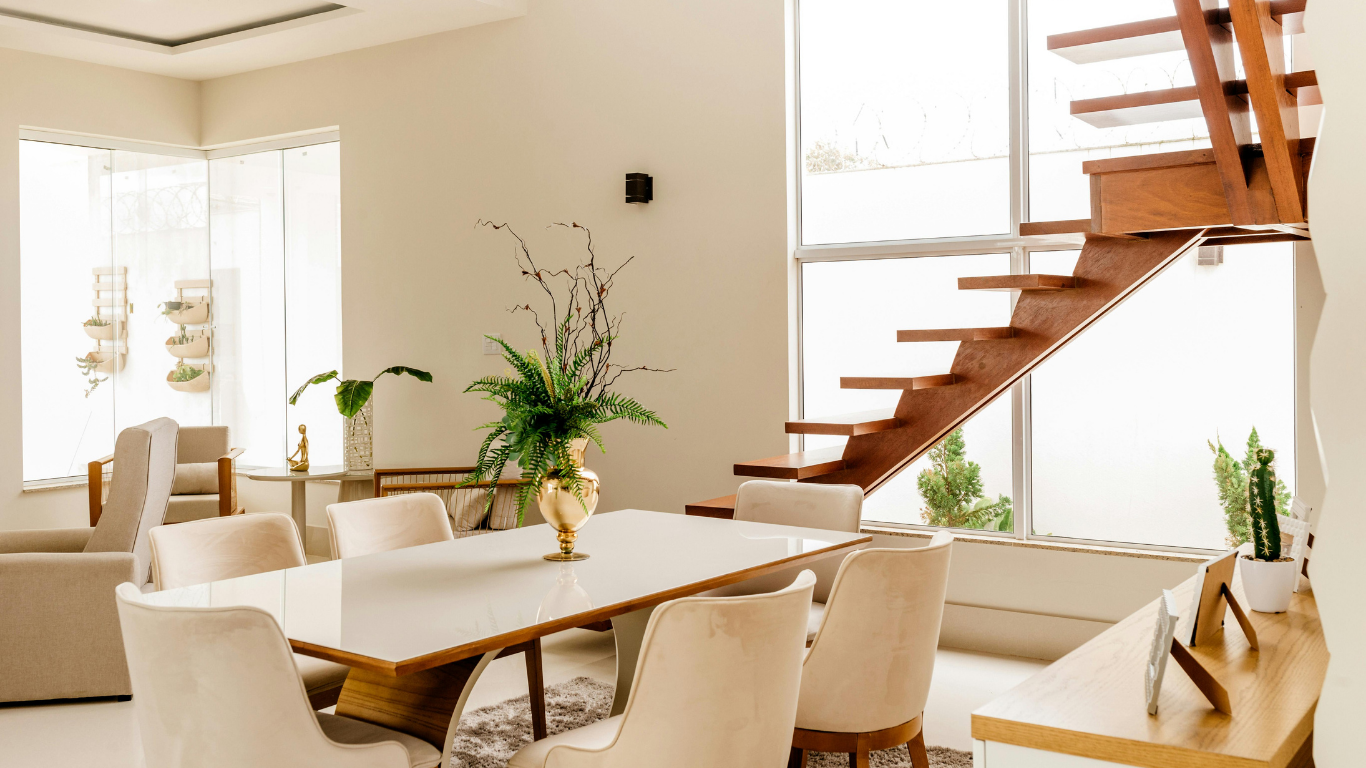 A modern dining room with neutral colors and an exposed stair case