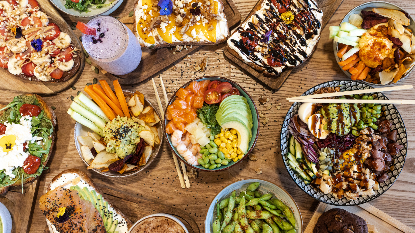 A spread of prepared foods across a wooden dinner table from a flat-lay perspective