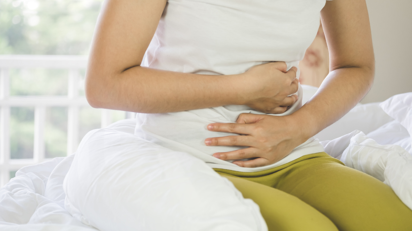 A woman in a white shirt clutches her stomach