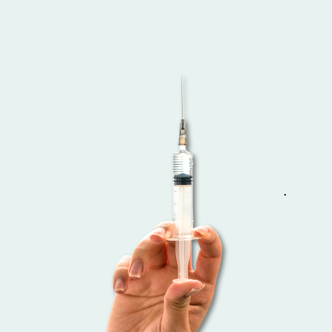 A hand is holding up a syringe with liquid in it