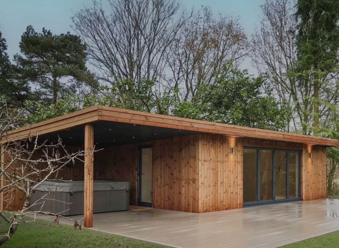 Wooden cabin with a covered hot tub area and sliding glass doors.