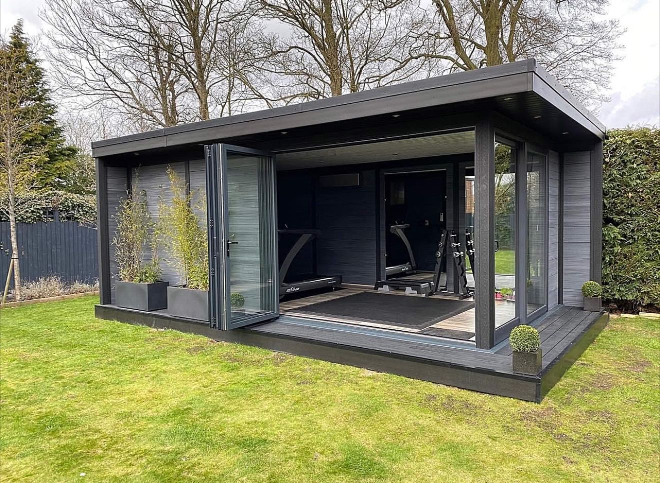 Black outdoor gym with glass doors on a grassy lawn.