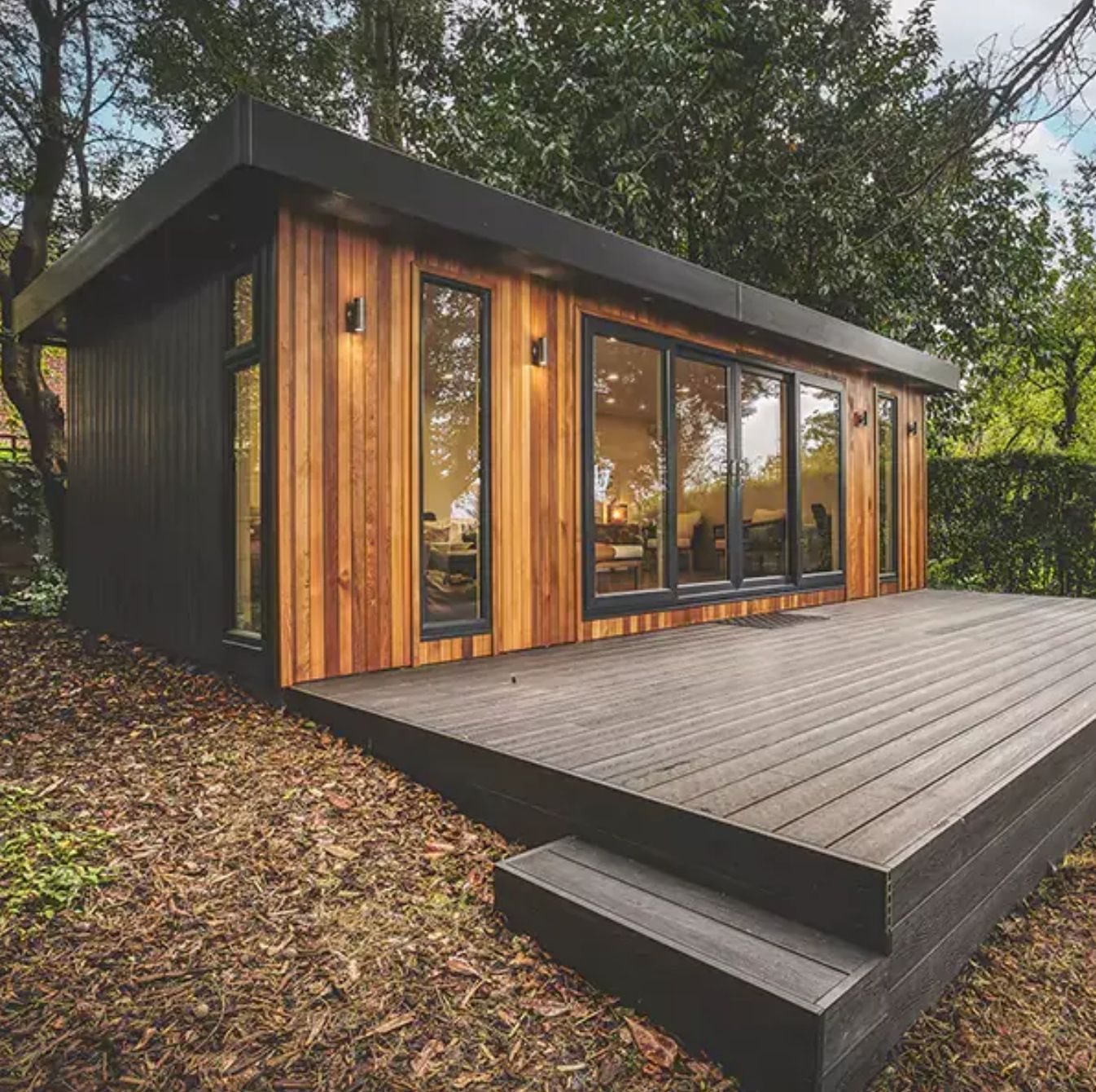 Modern wooden garden office with black accents, deck, and large windows.