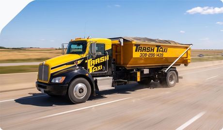 Yellow and black Tash Taxi dump truck driving on a road in a flat, open landscape