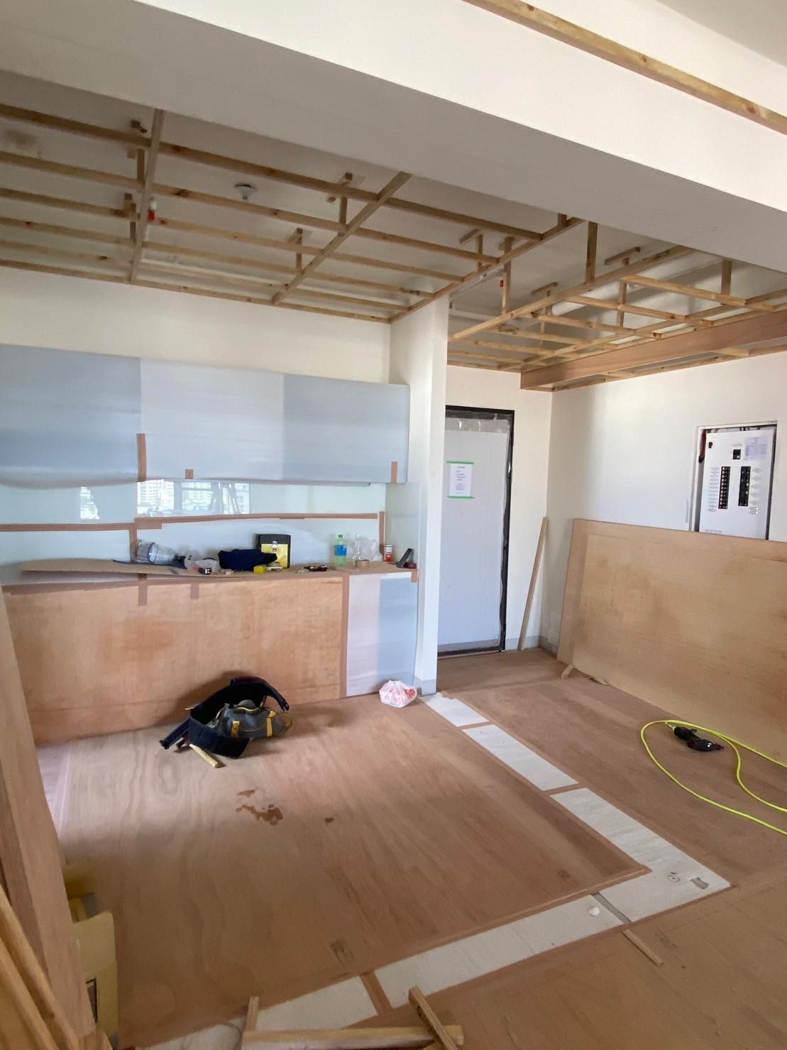 A room with a wooden floor and a kitchen in the background.