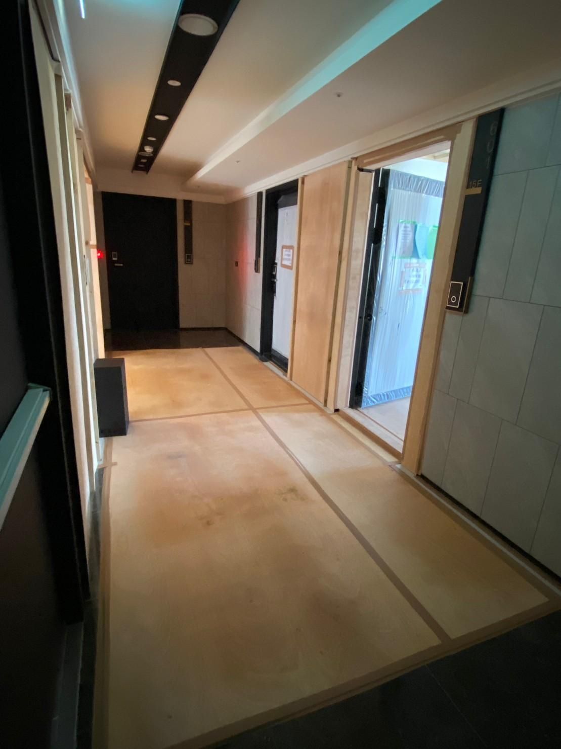A long hallway with a wooden floor and a lot of doors.