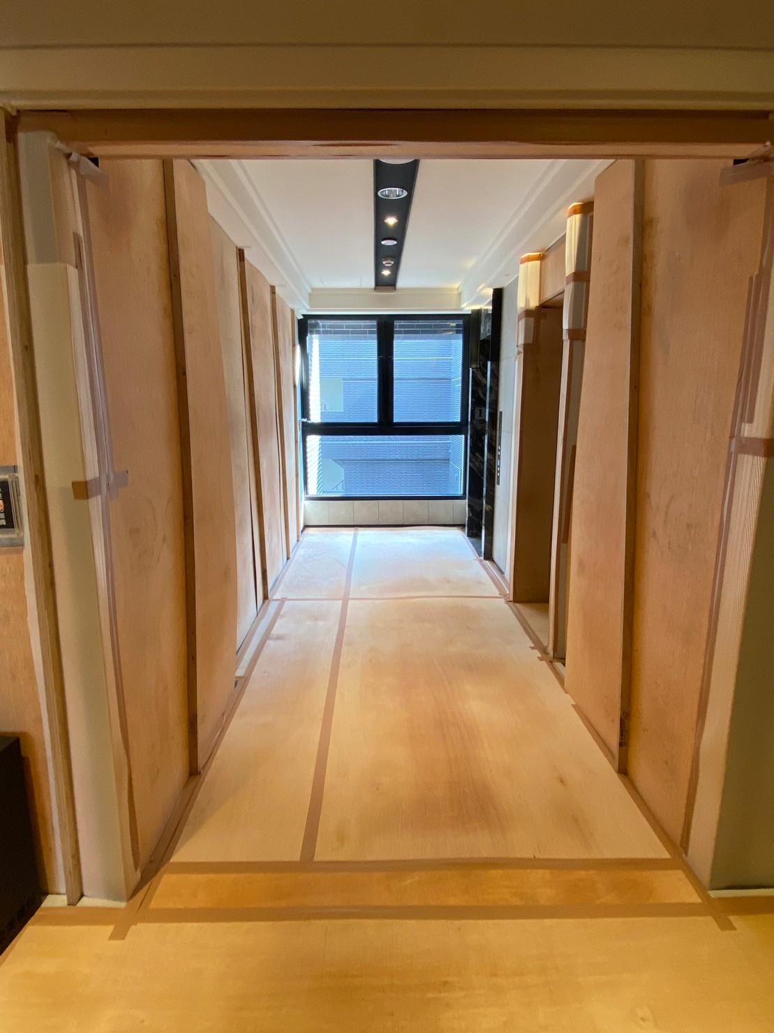 A long hallway with a wooden floor and a window.