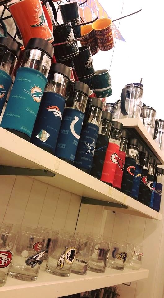 Two shelves stocked with various NFL team-branded insulated water bottles and drinking glasses.