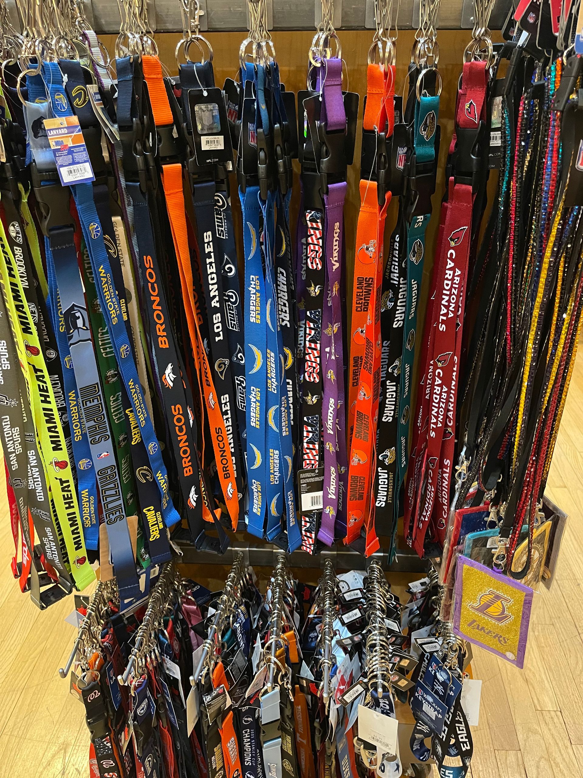 A retail rack filled with numerous colorful, patterned lanyards featuring various sports team logos and designs.
