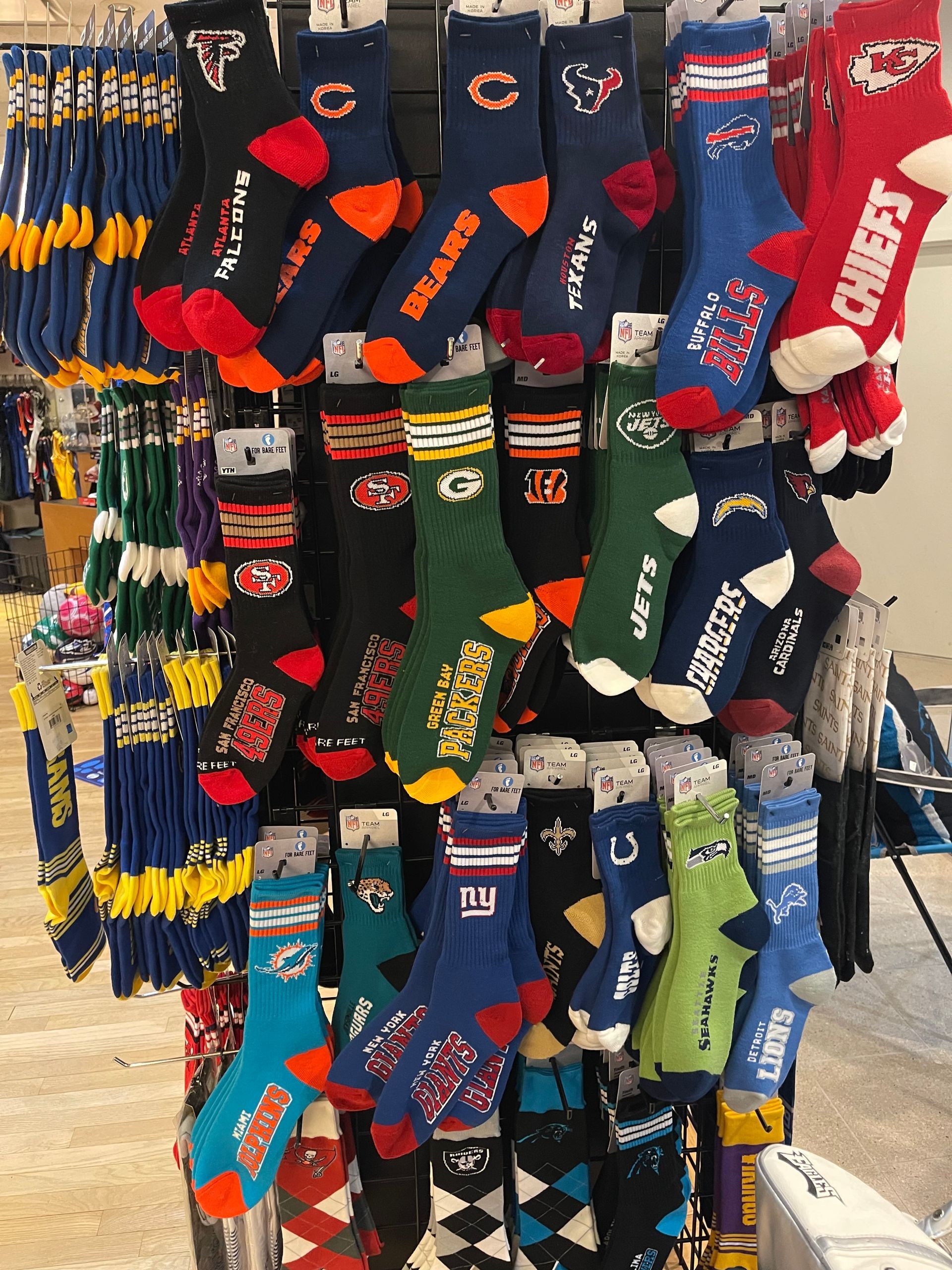 A retail display rack featuring an assortment of NFL-branded crew socks in various team colors and logos.