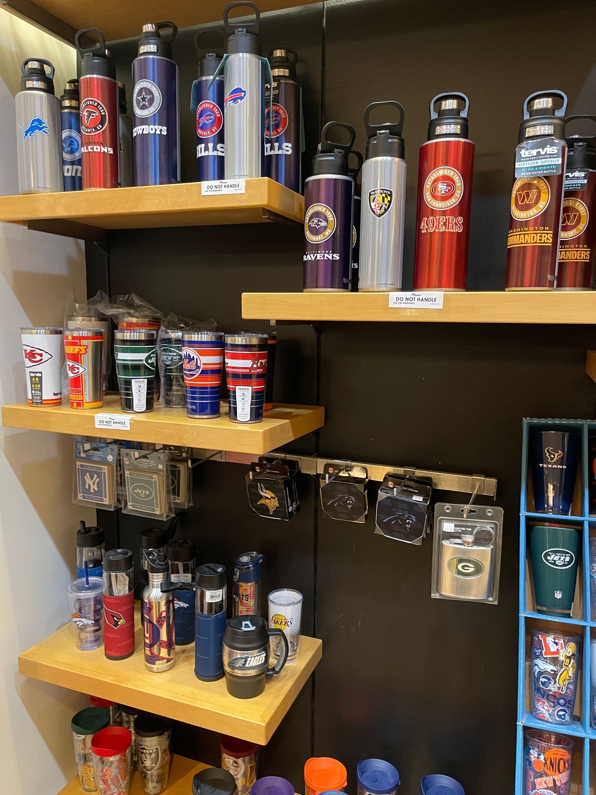 Shelves displaying various branded water bottles, tumblers, and mugs in a retail store setting.