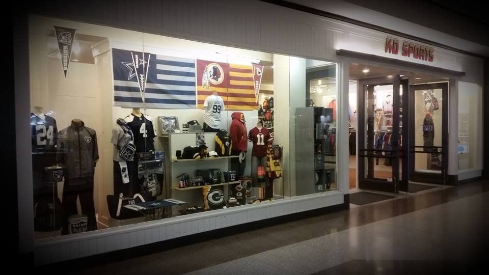 A store display window for a sports shop showing jerseys, apparel, and NFL flags, including the Washington Redskins logo.