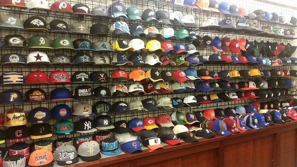 A grid display wall filled with many colorful sports team baseball caps in a retail store.