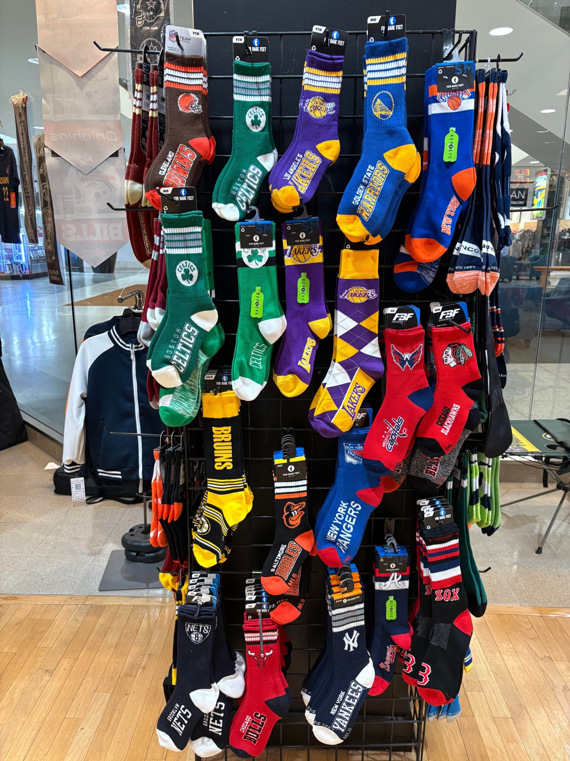 A store display rack holding various sports-themed crew socks with team logos and colors.