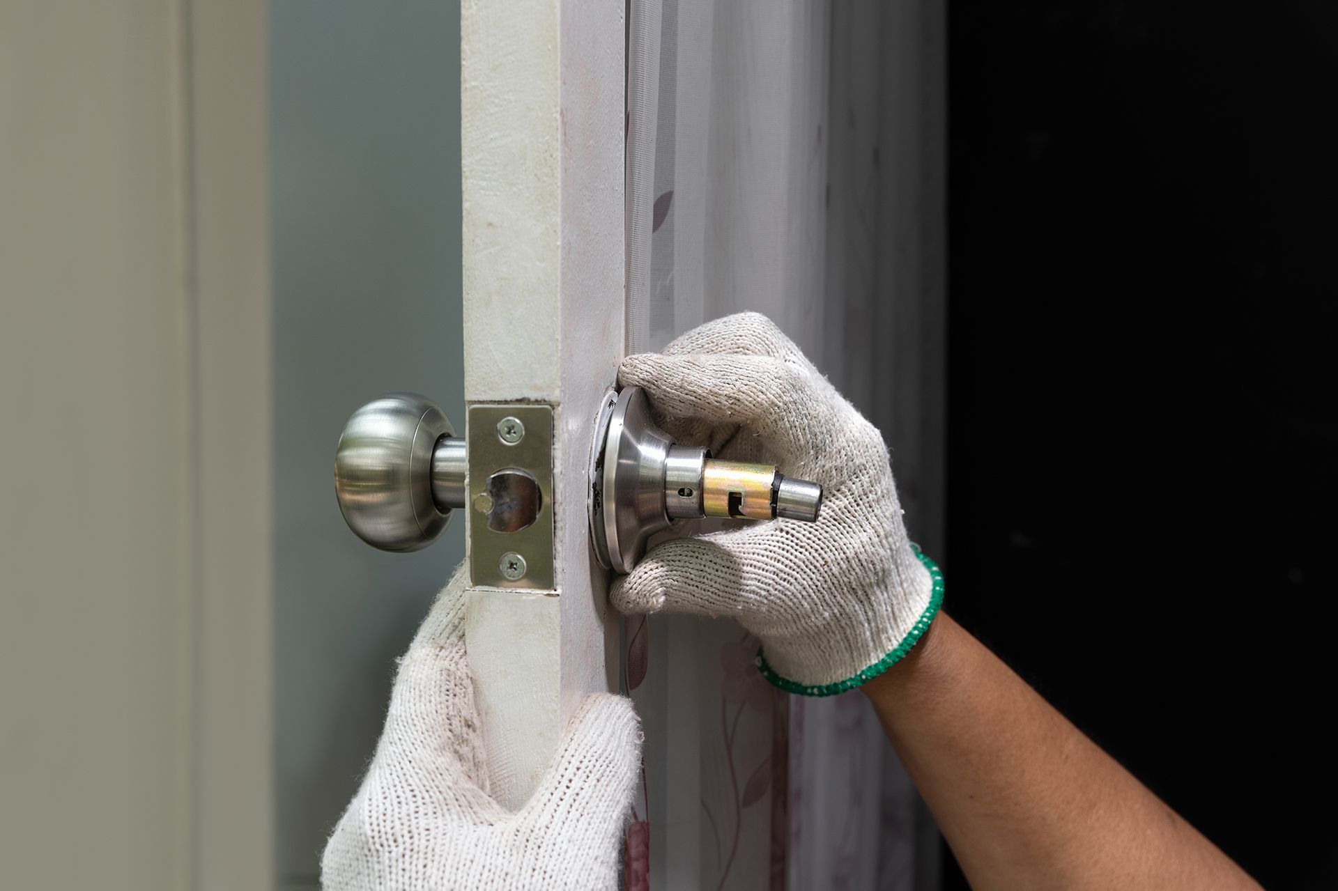A person is installing a door knob on a door.