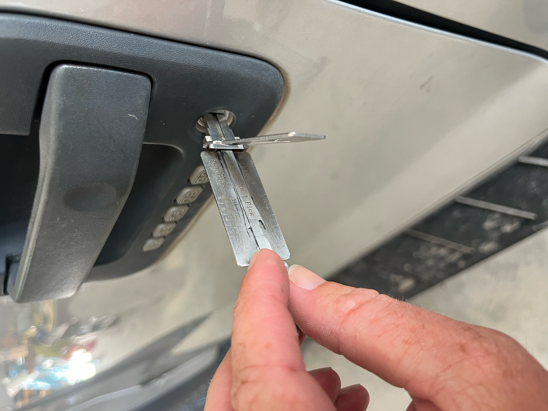 A person is holding a key in front of a car door.