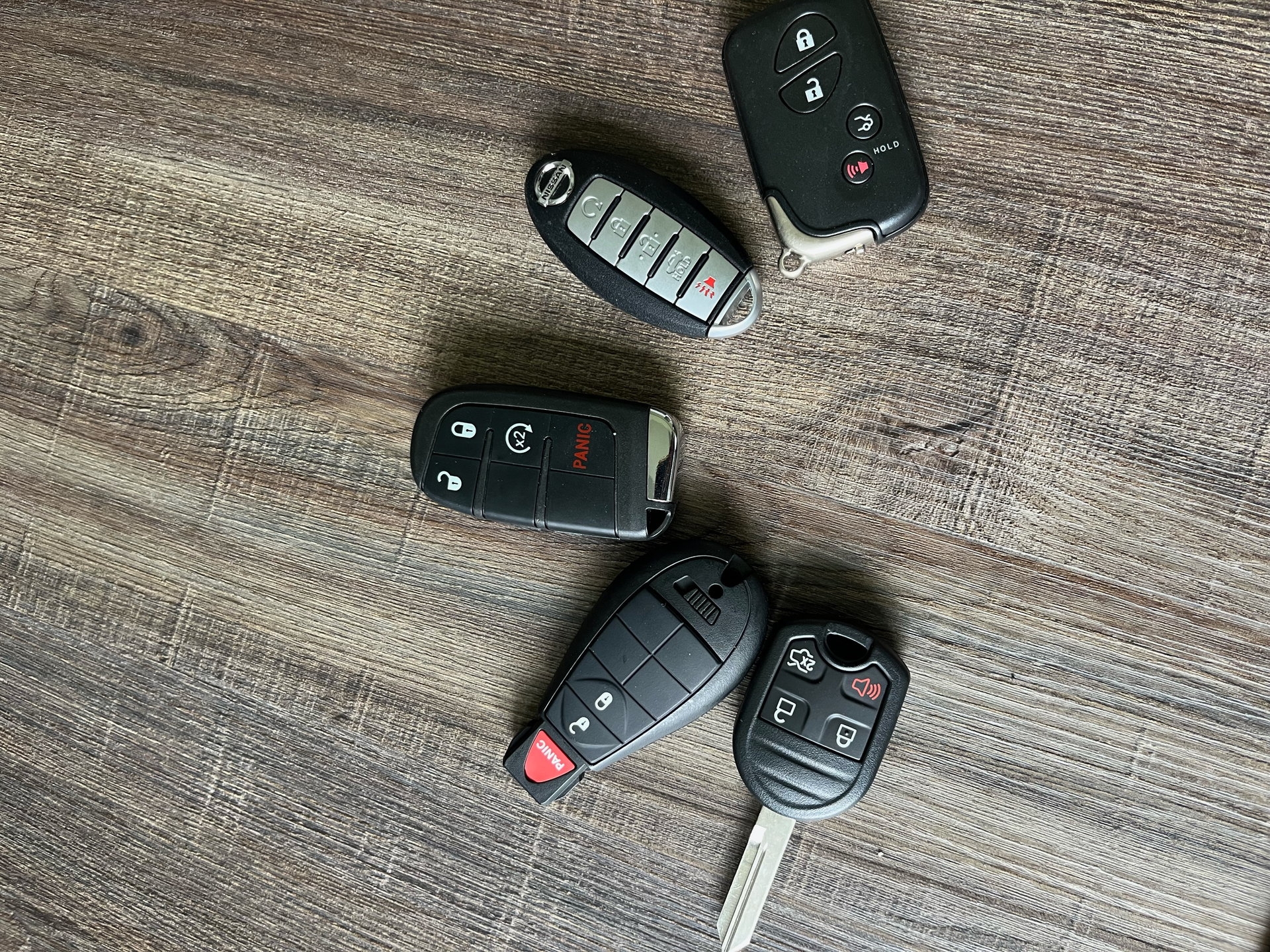 A bunch of car keys are laying on a wooden table.