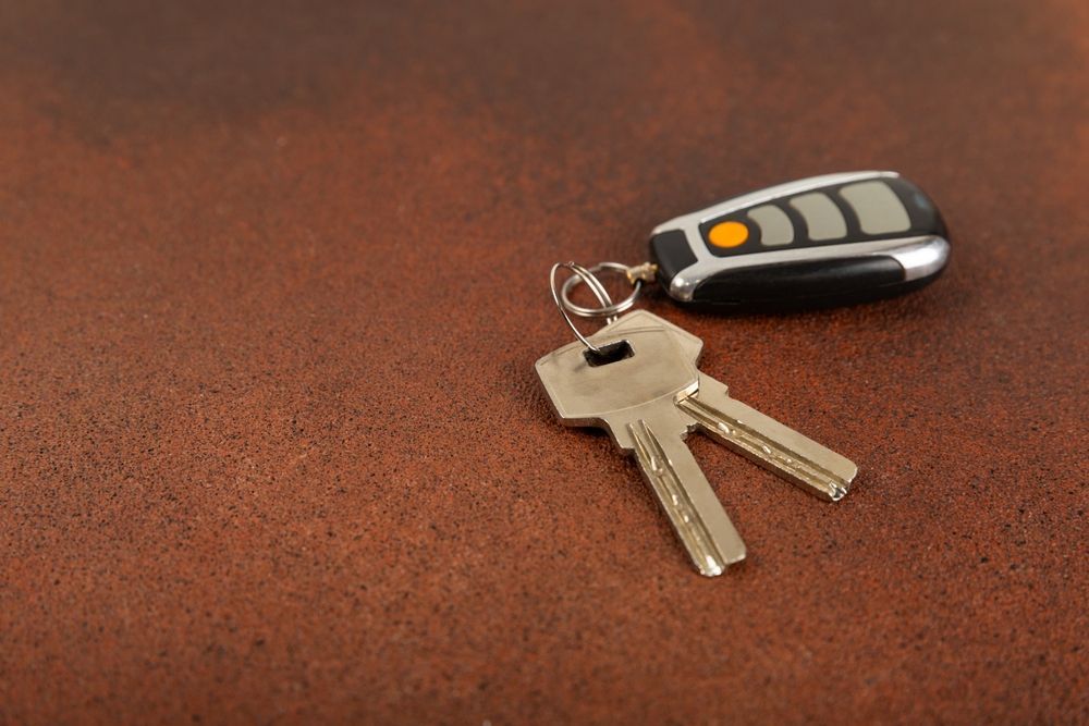 A pair of keys and a car key fob on a brown surface.