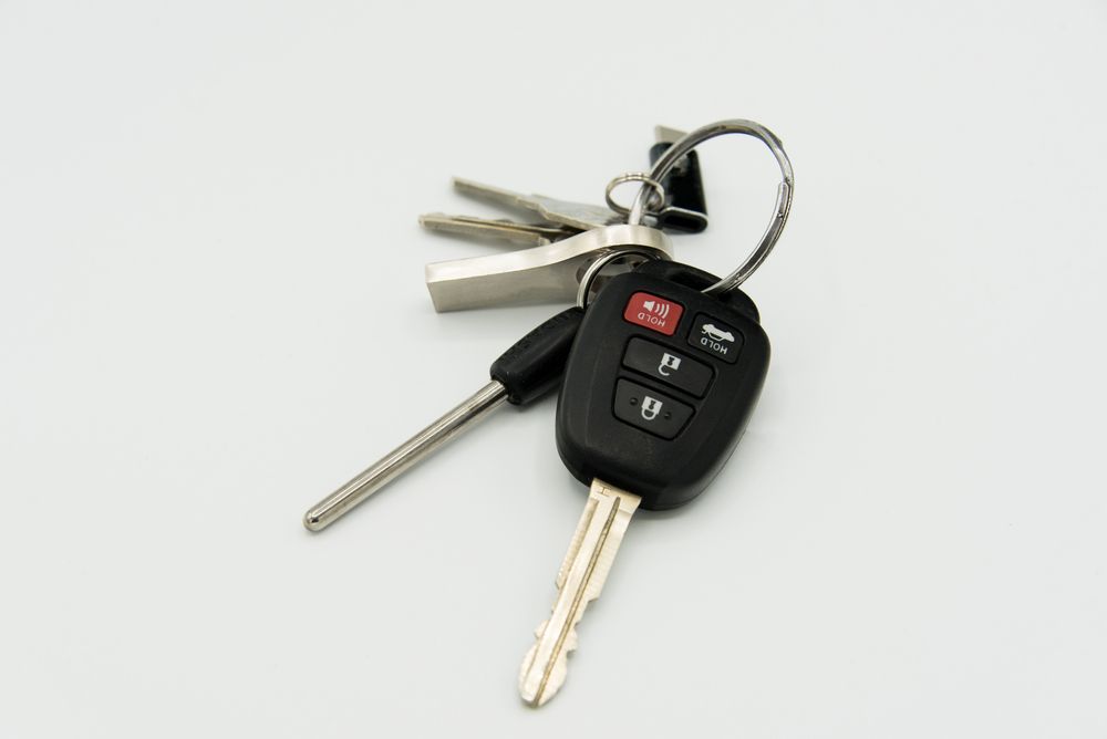 A bunch of car keys sitting on top of each other on a white surface.