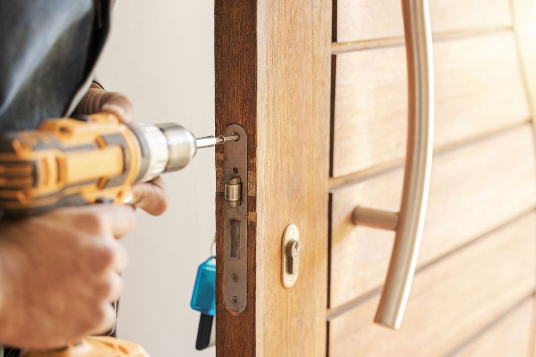 A man is fixing a door with a drill.
