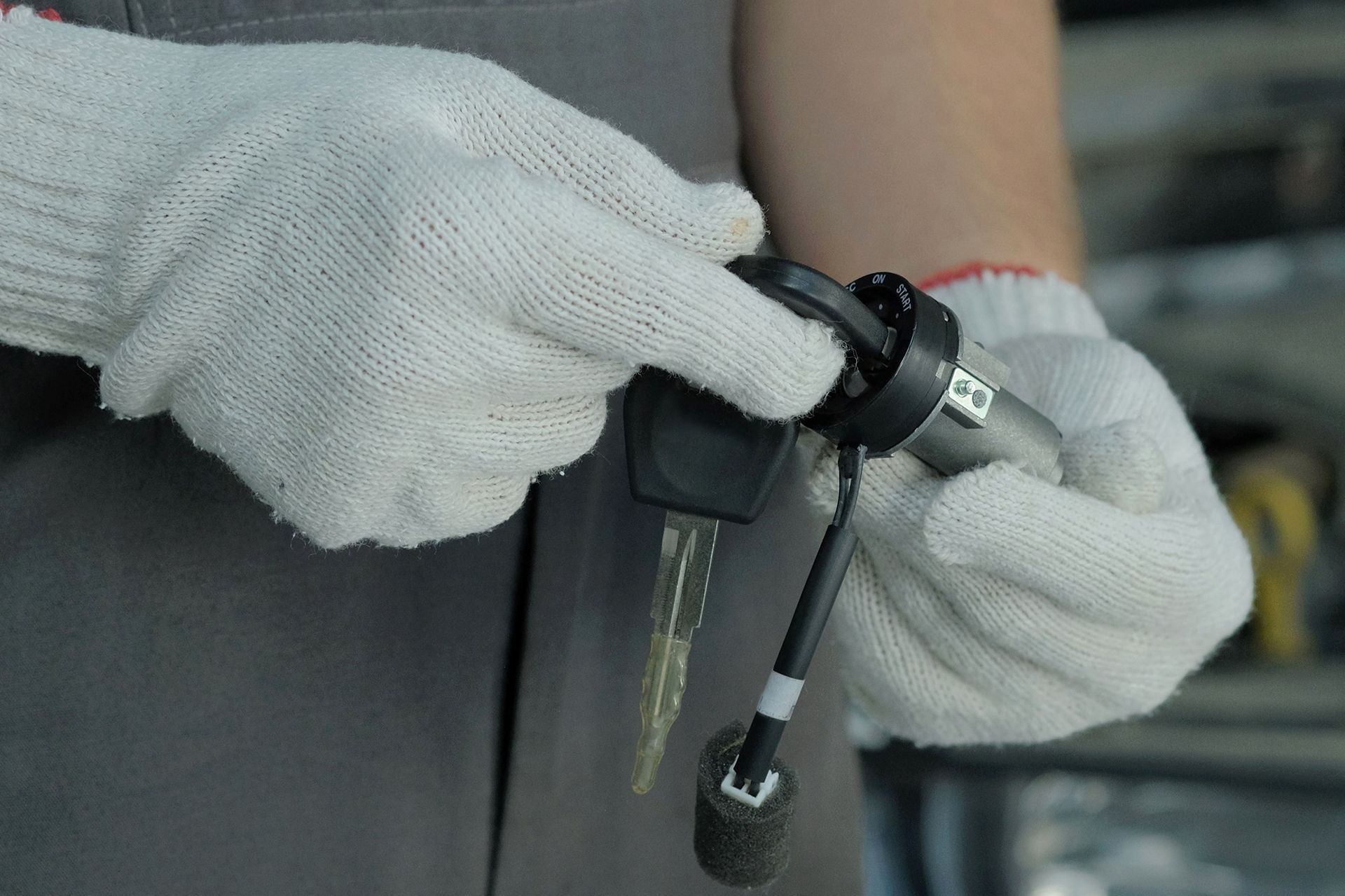 A person wearing gloves is holding a car key.