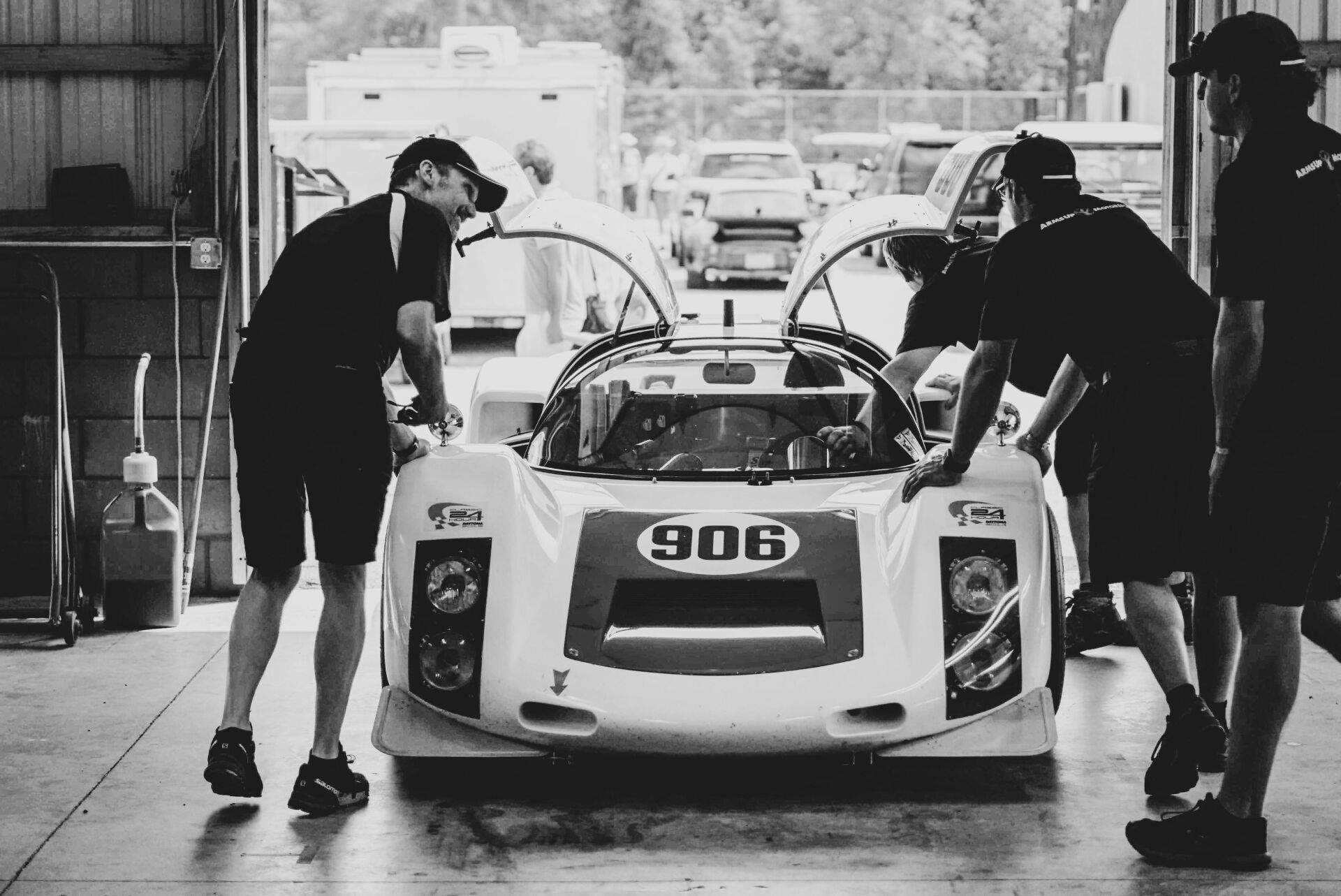 Race car with team in garage, preparing for race.