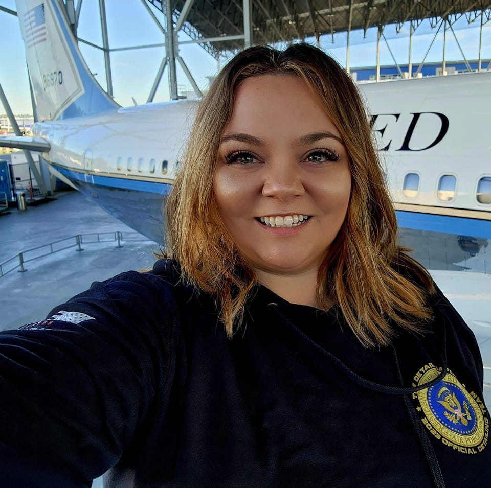A woman is taking a selfie in front of a united airlines plane.