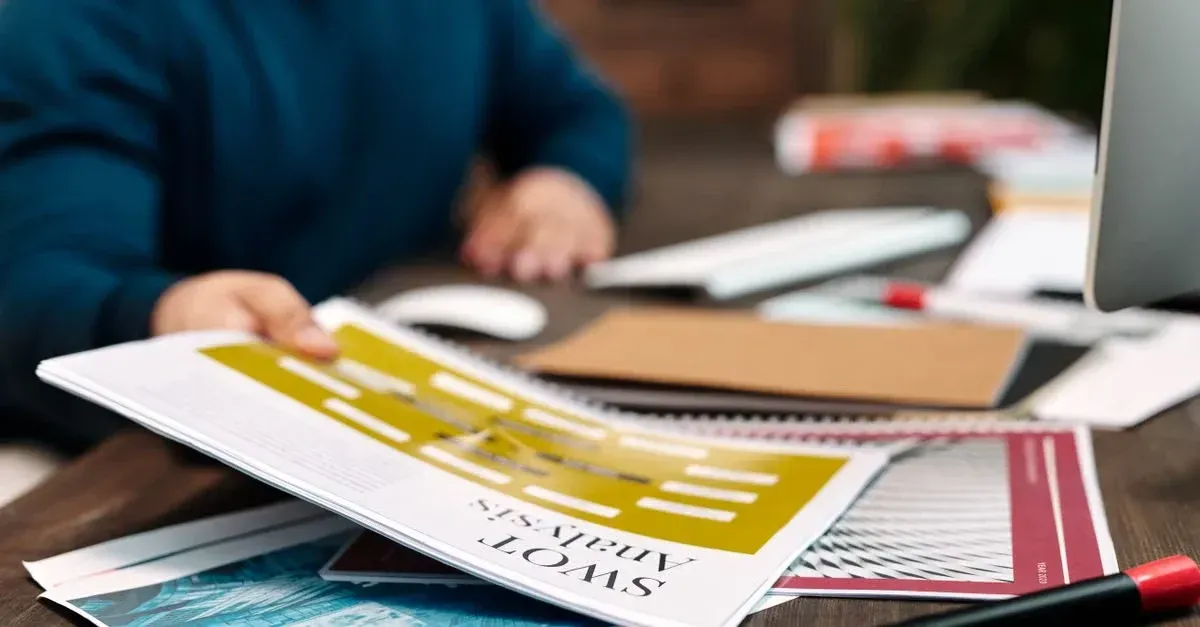 Designer reviewing auto tinting marketing materials and color samples at workspace desk.