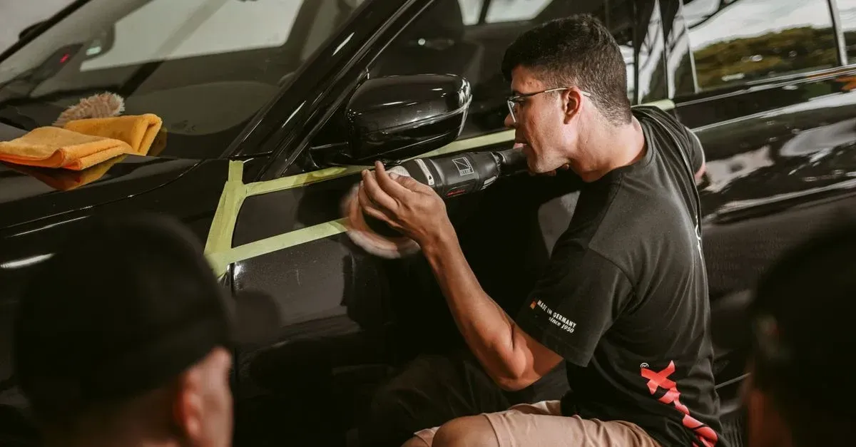 Professional auto detailing technician using precision tools for car interior cleaning and maintenance work.
