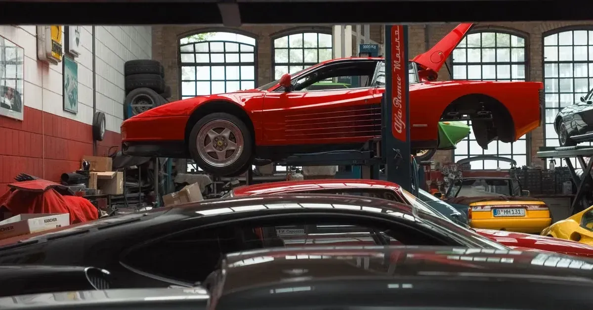 Red sports car lifted on hydraulic jack in professional auto detailing workshop.