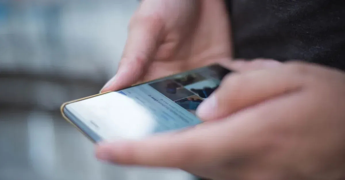 Hands holding smartphone displaying car detailing website design with professional layout.