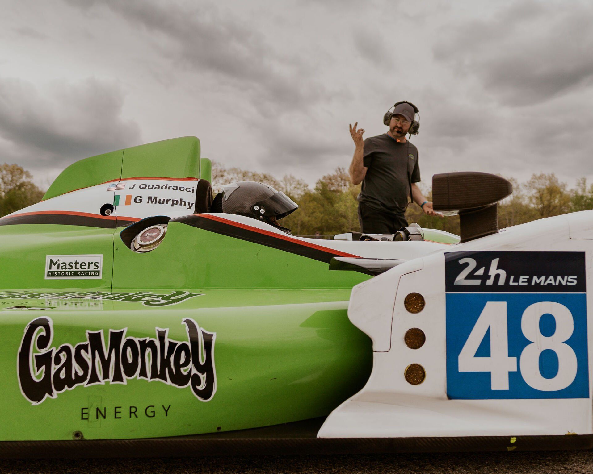 Man waving near a green and white race car with