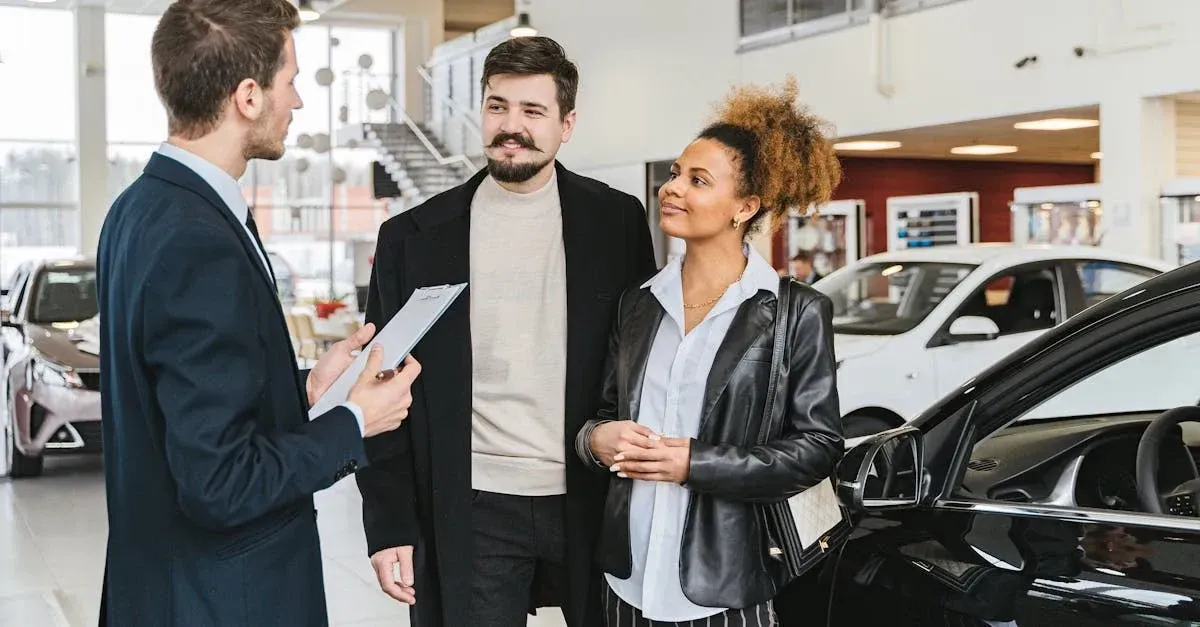 A car salesperson discusses options with a smiling couple in a bright showroom filled with cars.