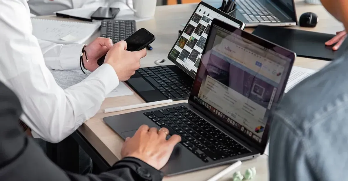 Two professionals analyzing digital marketing automotive data on laptop and smartphone at office. 