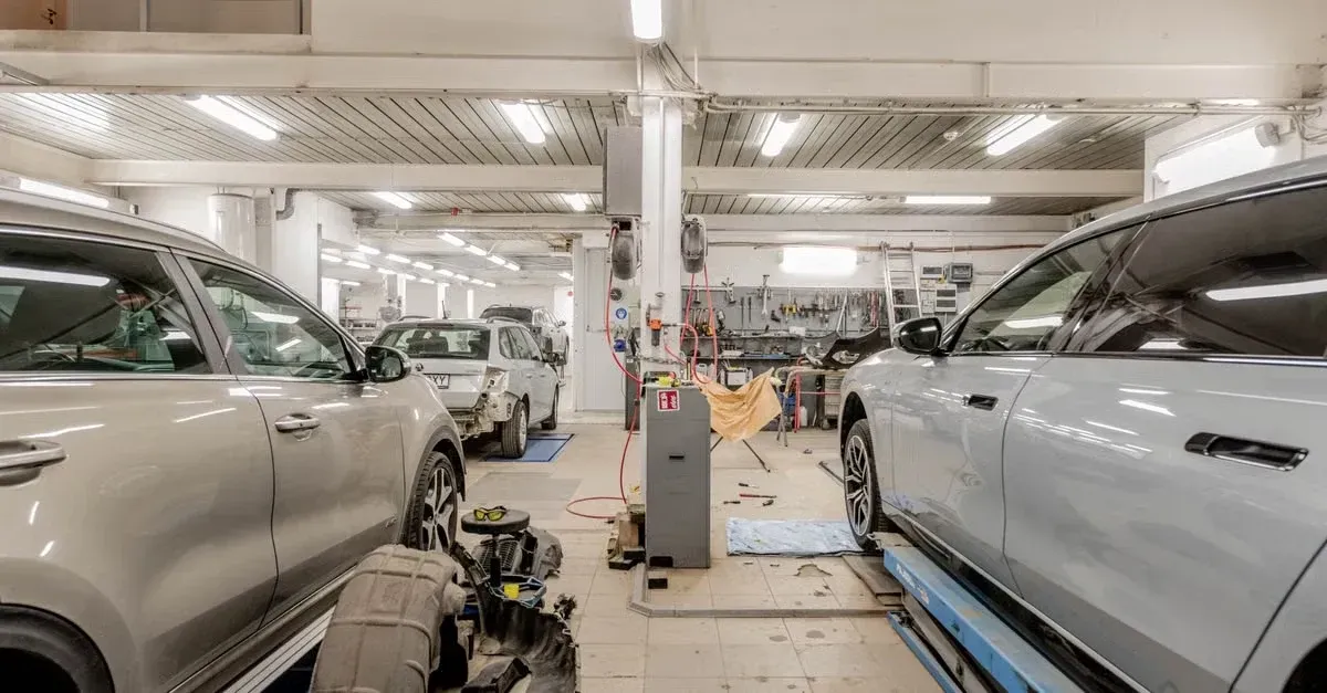 Professional automotive service bay with vehicles on lifts and technicians performing repairs.