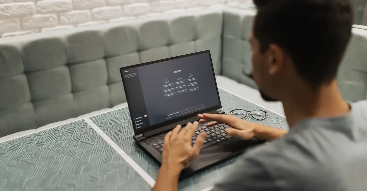 Man typing on laptop with CRM automotive industry software interface displayed on screen at desk.
