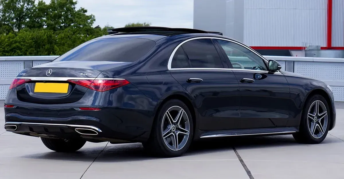 Dark blue sedan with tinted windows parked outside industrial building, showcasing window tint business potential.