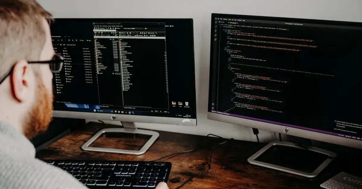 Developer working with dual monitors displaying code and window tint SEO optimization strategies.